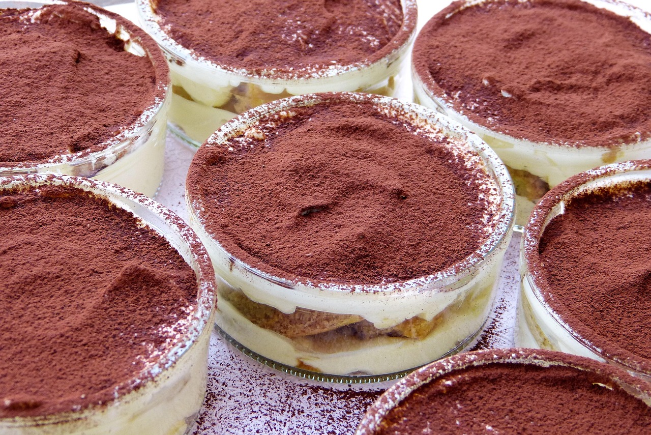 Tiramisù cremoso su un piatto, decorato con cacao e cioccolato grattugiato.