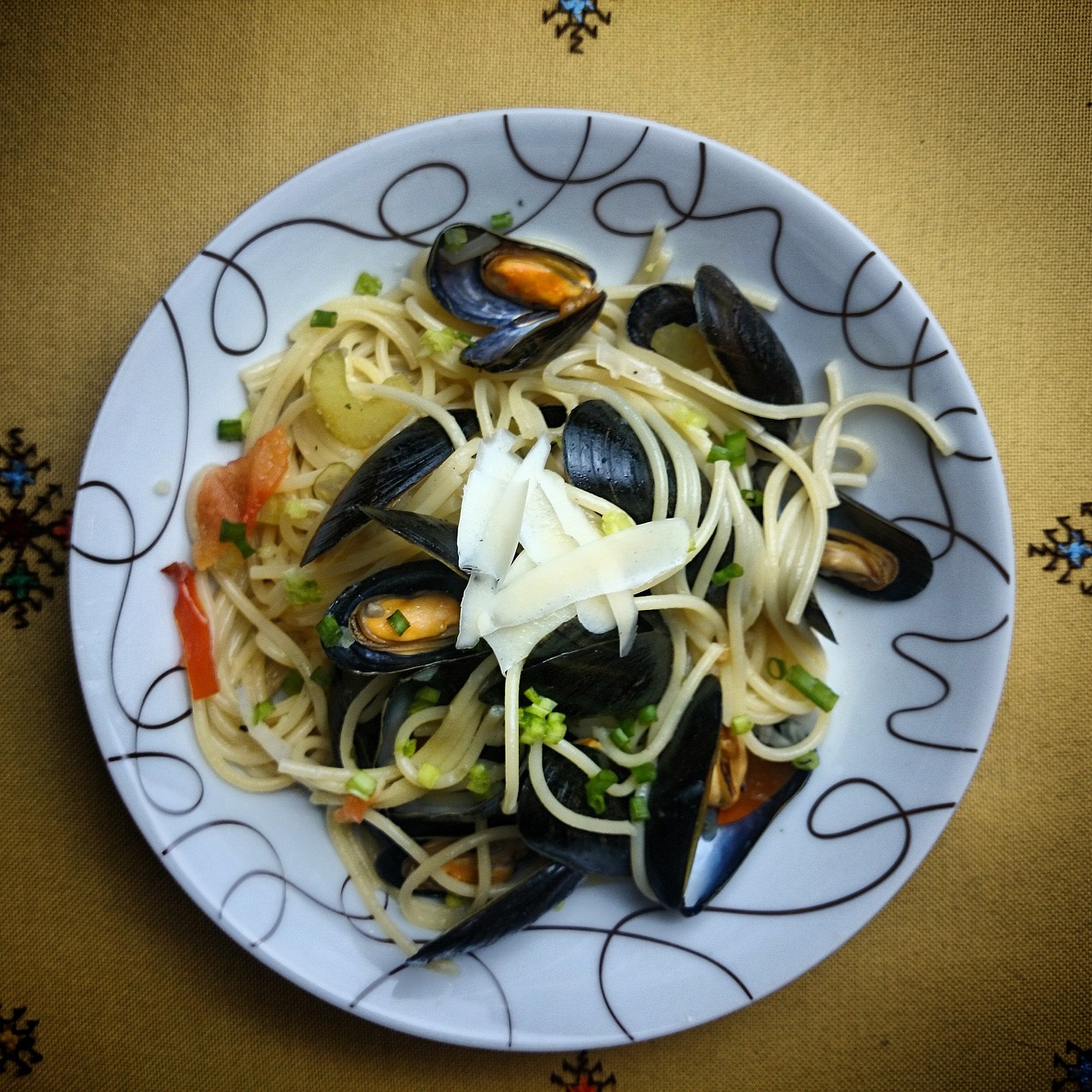 Piatto di pasta con cozze e pecorino, decorato con prezzemolo fresco.