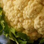 Cavolfiore al forno croccante, golden e appetitoso, servito su un piatto bianco.