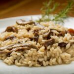 Piatto di risotto ai funghi cremoso, guarnito con prezzemolo fresco e funghi porcini.
