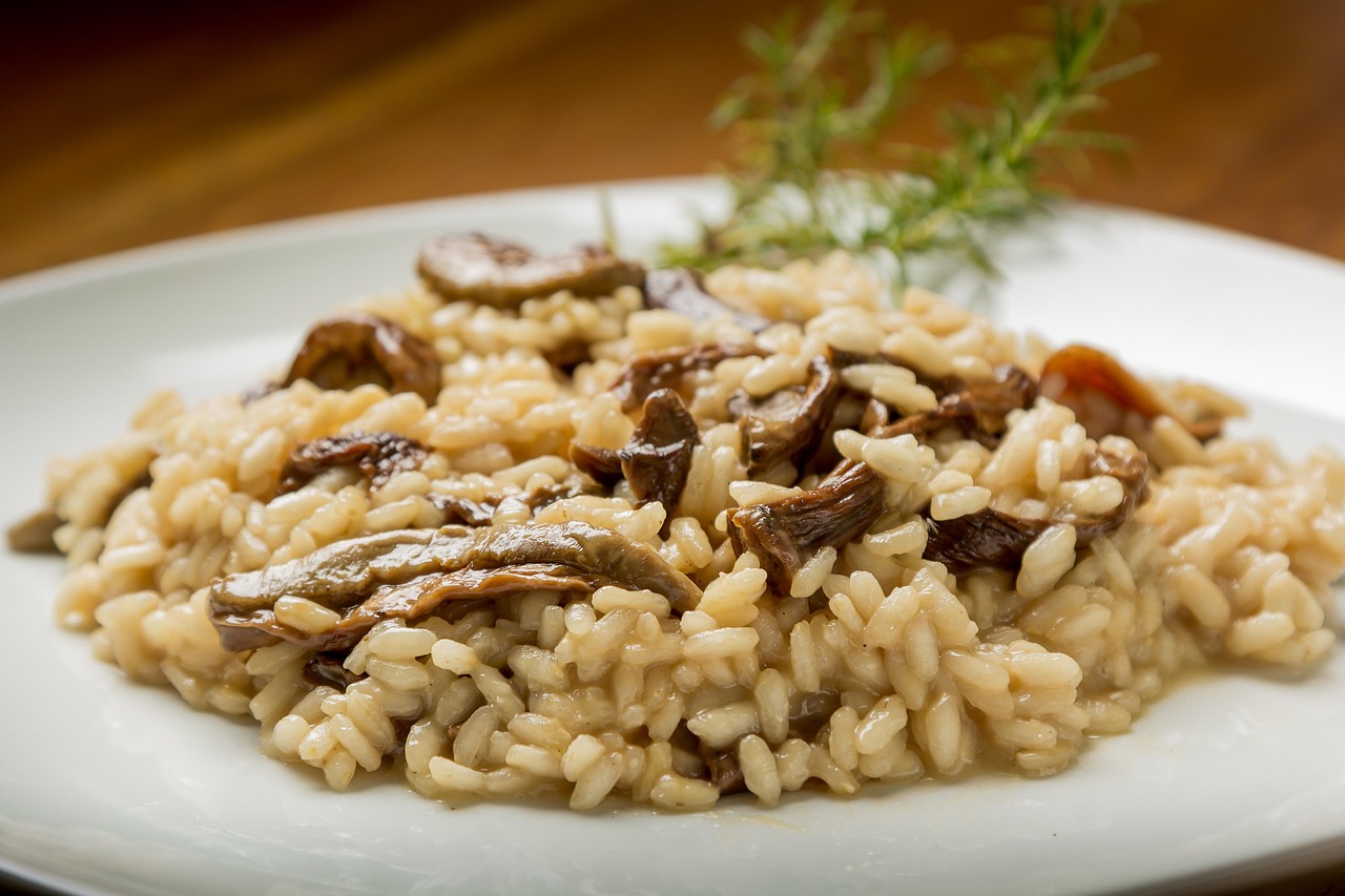 Piatto di risotto ai funghi cremoso, guarnito con prezzemolo fresco e funghi porcini.