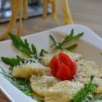 Ravioli di ricotta e spinaci freschi su un tavolo di legno, pronti per essere cotti.