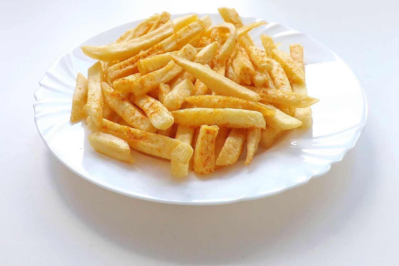 Patatine fritte croccanti su un piatto, con un fondo di olio da cucina e spezie, pronte da gustare.