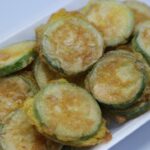 Frittelle di zucchine dorate con mozzarella filante che esce, servite su un piatto.