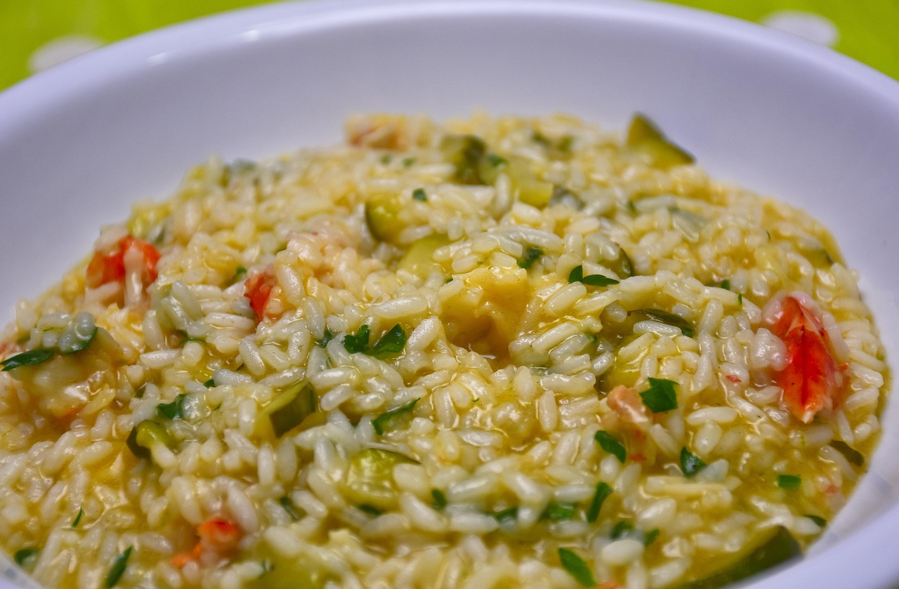 Risotto alla milanese cremoso, con una spolverata di parmigiano e zafferano, servito in un piatto bianco.