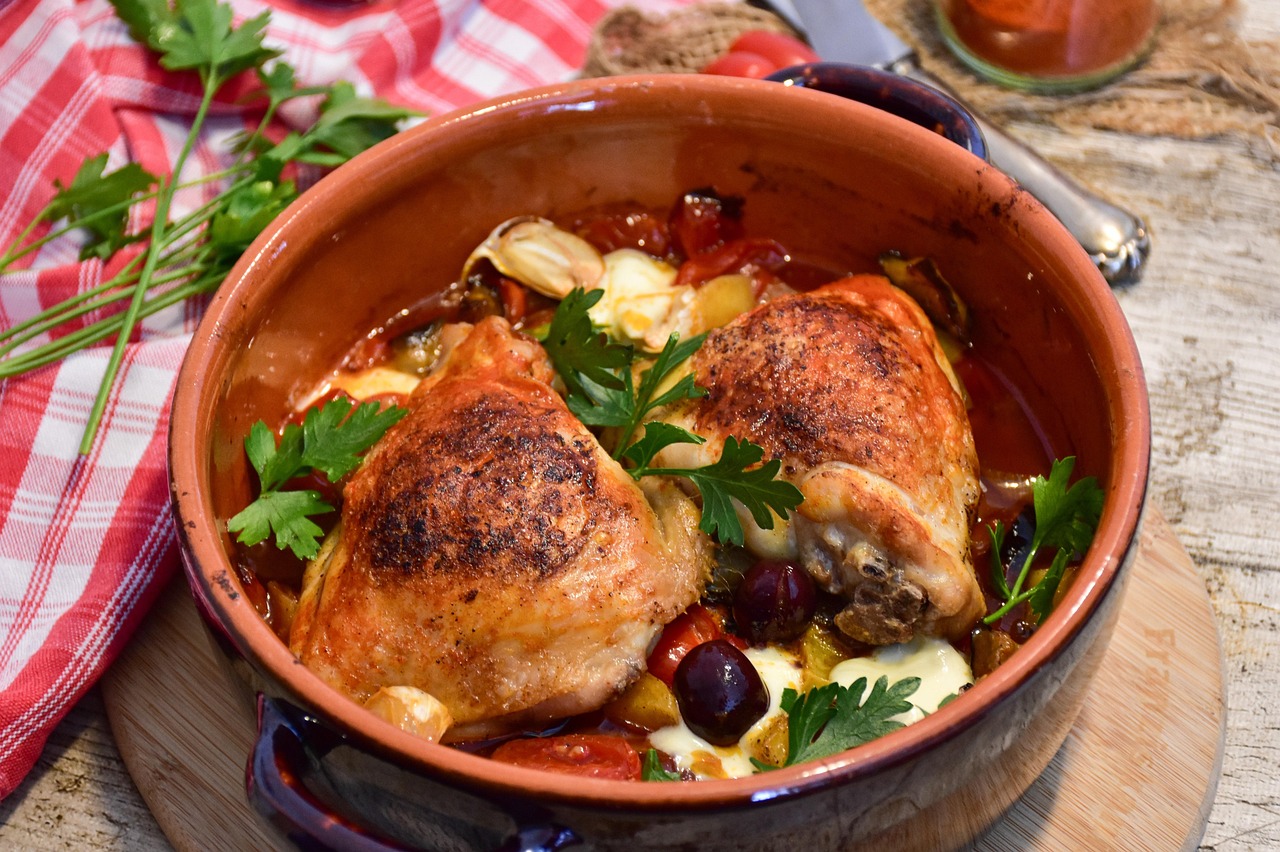 Pollo alla cacciatora servito in un piatto rustico, con pomodori, olive e erbe aromatiche.