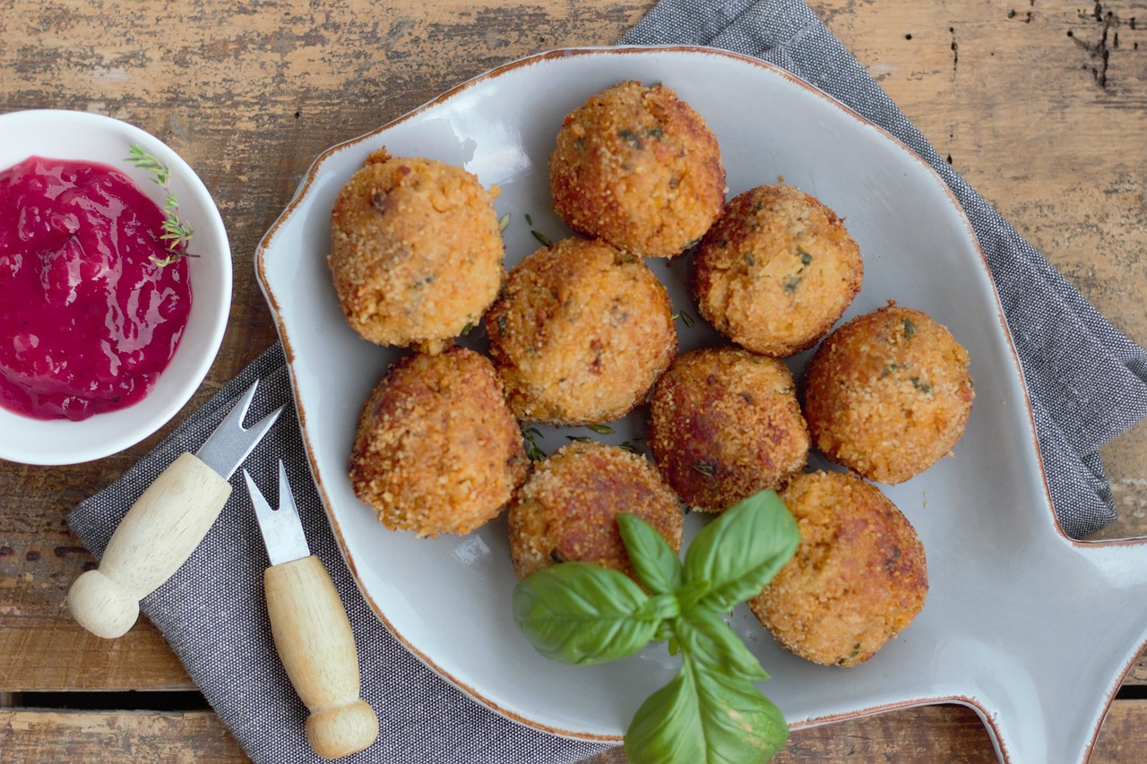Arancini siciliani dorati e croccanti, serviti su un piatto con salsa di pomodoro.