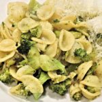 Pasta con broccoli e salsiccia, piatto gustoso e colorato, servito in un piatto bianco.