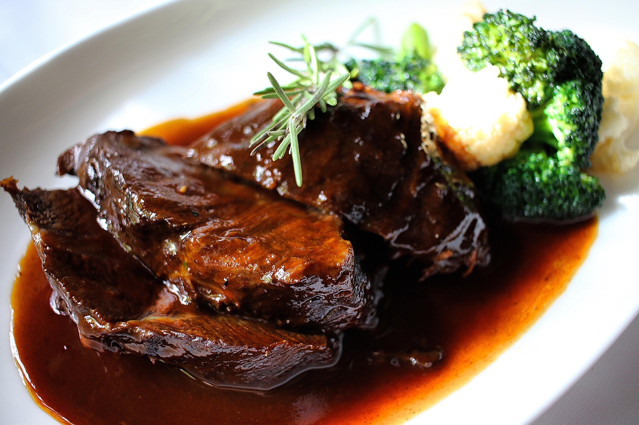 Brasato al vino rosso servito su un piatto, con contorni di verdure e salsa ricca.