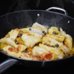 Baccalà alla vicentina in un piatto, pronto per essere servito, con contorni tradizionali.