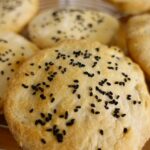 Pane croccante appena sfornato, dorato e tagliato a fette, servito su un tagliere di legno.