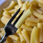 Pasta avanzata riscaldata, perfettamente al dente, servita in un piatto elegante.