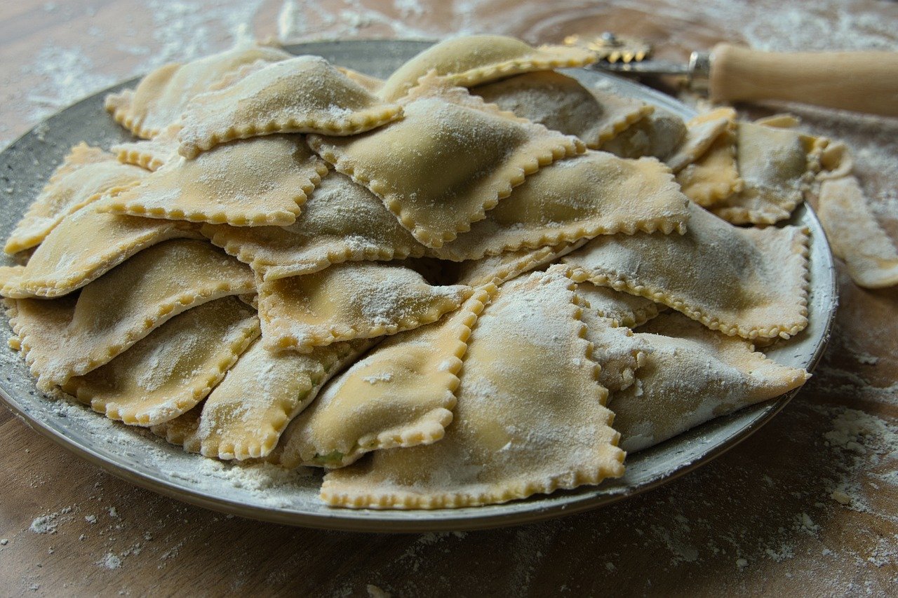 Ravioli freschi con ripieno cremoso su un tavolo di legno, pronti da cuocere.