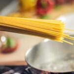 Pasta in cottura con ingredienti per evitare gonfiore, pentola sul fornello.