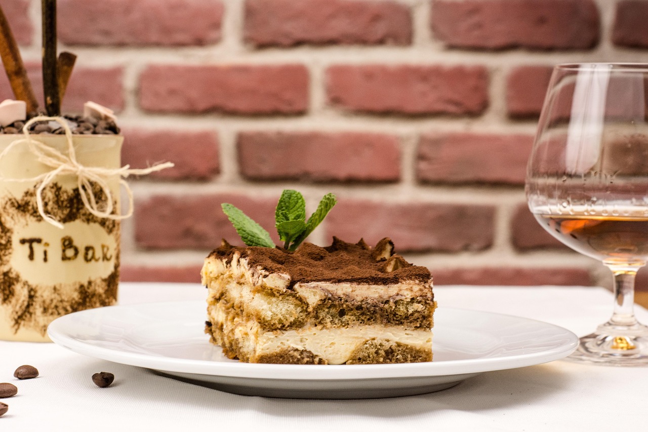 Fetta di tiramisù originale con crema e cacao, su piatto bianco decorato.