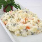 Insalata russa colorata con verdure e maionese, servita in una ciotola elegante per le feste.