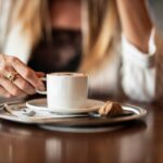 Tazza di caffè fumante su tavolo, simbolo di pausa dopo pranzo per favorire la digestione.