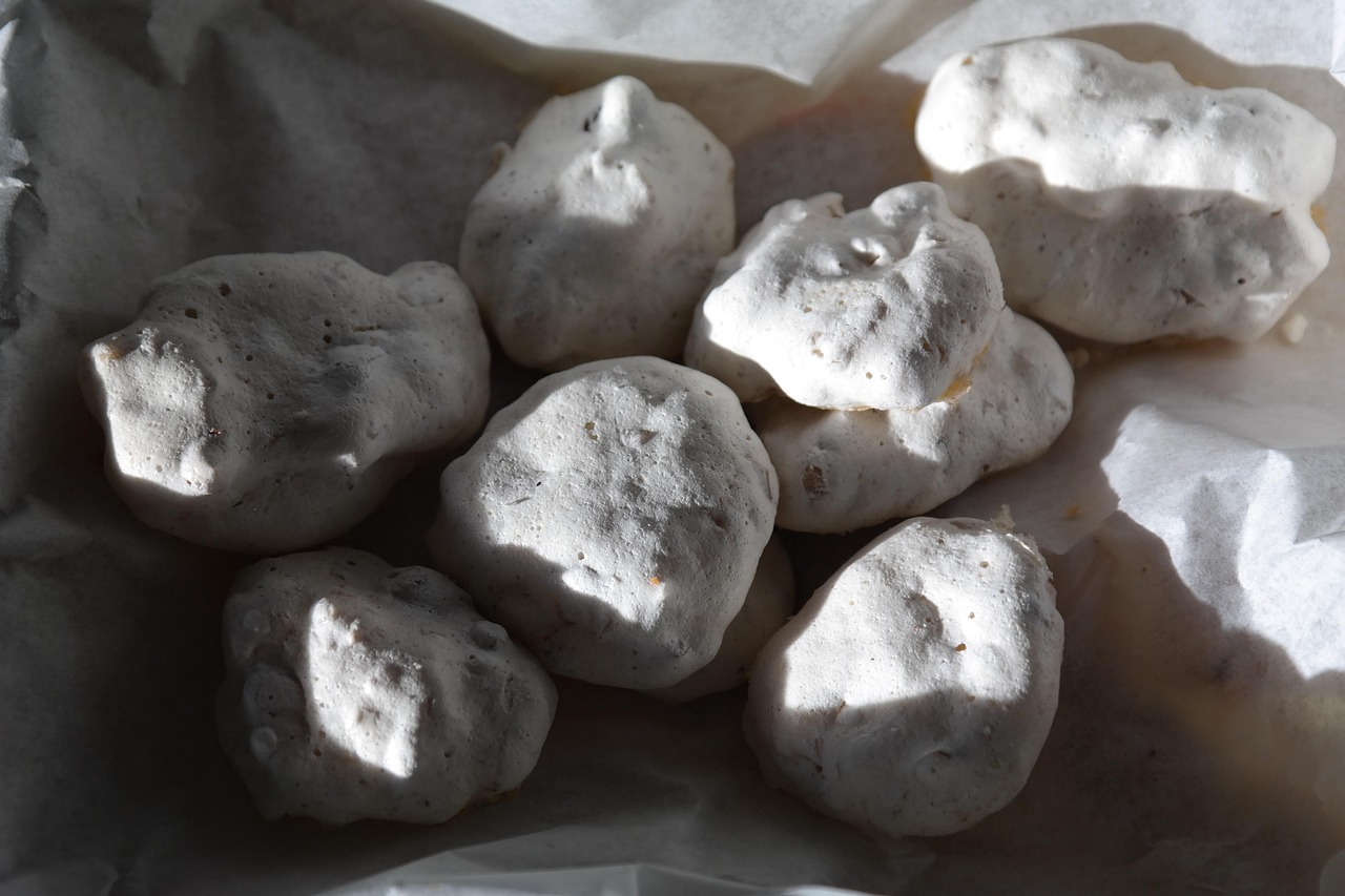 Meringhe bianche disposte su una teglia, pronte per la cottura in forno bassissimo con sportello socchiuso.