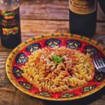 Piatto di pasta con tonno e burro, guarnito con erbe fresche, pronto da servire.