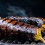 Melanzane grigliate marinate in una ciotola con spezie e olio d'oliva, pronte per essere servite.